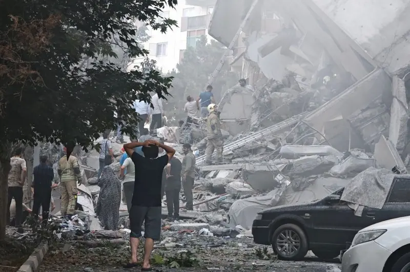 En esta foto del viernes, se observan rescatistas y población civil en un edificio gravemente dañado por los ataques israelíes en Teherán.