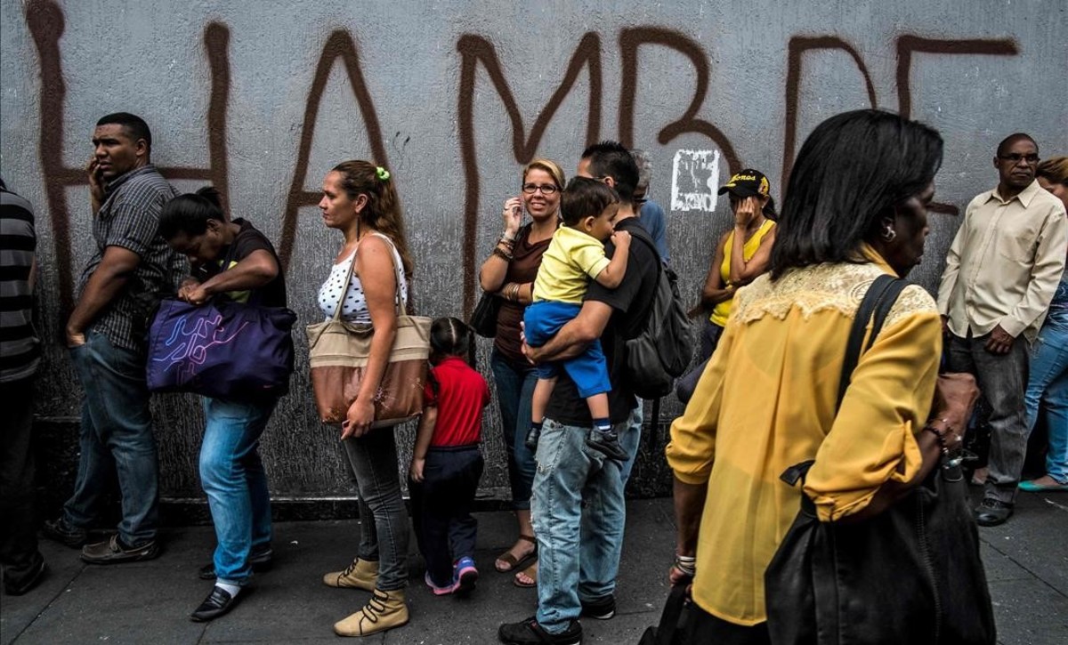 venezolanos-hacen-cola-frente-una-pintada-con-palabra-hambre-caracas-1532423731943